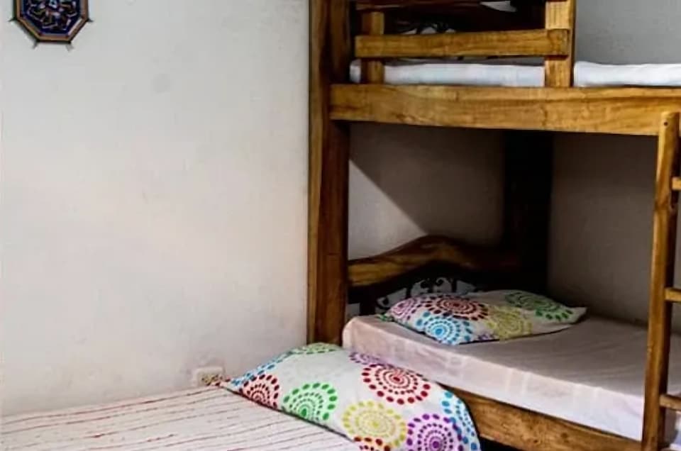 Habitación con literas de madera y cobijas con estampado de mandalas de colores (foto antigua de baja resolución).